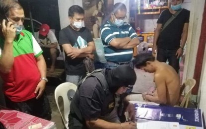 <p><strong>ANTI-DRUG OPERATION</strong>. Operatives of Bacolod City Police Station 7 arrest Reynaldo Gracilla (seated, right) at his residence in Purok Kabugwason, Barangay Mansilingan on Tuesday (March 16, 2021) night. A high-value individual, the suspect yielded seven grams of suspected shabu with a value of PHP47,600. <em>(Photo courtesy of Bacolod City Police Office)</em></p>