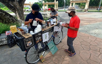 <p><strong>MOBILE COFFEE.</strong> Ruggierro Nicolae Rubio (left) prepares his coffee concoctions from his own mobile stand at the Rodelsa Rotunda in Cagayan de Oro City. The concept of putting up a mobile coffee shop started when Rubio lost his job as a barista at a local hotel. <em>(PNA photo by Nef Luczon)</em></p>