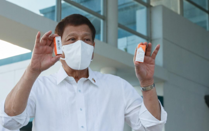 <p><strong>GOV’T-PROCURED VAX.</strong> President Rodrigo Duterte shows two vials of Sinovac’s CoronaVac vaccine during the arrival of the 1 million doses of CoronaVac Covid-10 vax at the Villamor Airbase in Pasay City on Monday (March 29, 2021). The 1 million doses are part of the first batch of the 25 million vials purchased by the Philippine government from Sinovac Biotech of China for the country’s vaccination program against Covid-19. <em>(Presidential photo)</em></p>