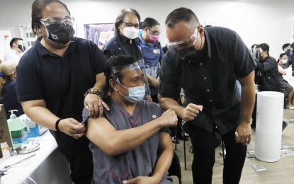 <p><strong>INOCULATED.</strong> Dr. Pascual Pattaui gets a fist bump from Taguig City Mayor Lino Cayetano (right) after getting his first shot of CoronaVac at the Lakeshore vaccination hub on March 2, 2021. Cayetano said the city is about 90 percent done inoculating healthcare workers. <em>(PNA photo by Avito C. Dalan)</em></p>