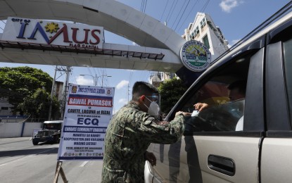 <p><strong>CHECKPOINT.</strong> Strict border controls, such as this policeman checking on a motorist along Aguinaldo Highway in Imus, Cavite on Thursday, will remain in the National Capital Region Plus for another week. Enhanced community quarantine was extended in Metro Manila, Bulacan, Cavite, Laguna, and Rizal from April 5 to 11, Malacañang announced on Saturday (April 3, 2021). <em>(PNA photo by Avito C. Dalan)</em></p>