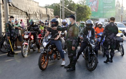 <p><strong>CHECKPOINT.</strong> Riders from Marikina City stop at the Anonas Police Station quarantine checkpoint along Aurora Boulevard, at the boundary of Marikina and Quezon City, in this March 31, 2021 photo. Justice Secretary Menardo Guevarra suggested on Monday (April 5, 2021) during a press briefing that local governments penalize violators with community services instead of sending them to jail. <em>(PNA photo by Joey O. Razon)</em></p>