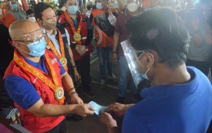 <p style="text-align: left;"><strong>URGENT TRANSACTION.</strong> Social Welfare and Development Undersecretary Glen Paje (left) hands over cash aid to a beneficiary shortly after the latter was verified, at the Caloocan High School in Caloocan City on Wednesday (April 7, 2021). Paje said the verification process to claim the aid was swift due to the digital database used by the local government unit and the help of financial service provider, Universal Storefront Services Corp.<em> (PNA photo by Robert Alfiler)</em></p>