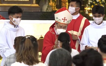 <p><strong>CONFIRMATION RITES</strong>. Palo, Leyte Archbishop John Du administers the chrism oil to a Roman Catholic faithful during the confirmation rites for 100 young members of the church, at the National Shrine of St. Joseph in Mandaue City, Cebu on Monday (April 12, 2021). Du, in his homily, highlighted the friendliness and hospitality of the Filipinos' ancestors as early expression of Christian values.<em> (Screengrab from Archdiocese of Cebu video)</em></p>