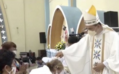<p><strong>BAPTISM FOR ADULTS</strong>. An old woman receives the sacrament of baptism from a bishop in special rites at the National Shrine of the Our Lady of the Rule in Lapu-Lapu City on Tuesday (April 13, 2021). The event was conducted on the third day of Triduum in preparation for the 500th anniversary of the First Baptism that happened in Cebu on April 14, 1521, to be celebrated on Wednesday at the Plaza Sugbu near the historic Basilica Minore del Sto. Niño de Cebu and the Magellan's Cross. <em>(Screengrab from an Archdiocese of Cebu video)</em></p>