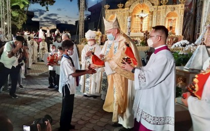 <p><strong>'FIRST BAPTISM'.</strong> Apostolic Nuncio to the Philippines Archbishop Charles John Brown presents an image of the Sto. Niño to a boy who was one of the seven children baptized during the solemn Pontifical Mass beside the Magellan's Cross at the Plaza Sugbu in Cebu City, on Wednesday (April 14, 2021). The activity was part of the celebration for the 500th anniversary of Christianity in the Philippines. <em>(PNA photo by John Rey Saavedra)</em></p>