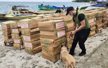 <p><strong>SMUGGLED.</strong> A K9 unit of the Philippine Drug Enforcement Agency inspects the confiscated smuggled cigarettes to ensure no illegal drugs are mixed with the confiscated contrabands. A team of Navy and Bureau of Customs personnel seized the assorted smuggled cigarettes worth some PHP10.7 million while conducting maritime patrol at dawn Thursday (April 15, 2021) at vicinity seawaters off Barangay Sinunuc, Zamboanga City.<em> (Photo courtesy of the Naval Forces Western Mindanao Public Affairs Office)</em></p>