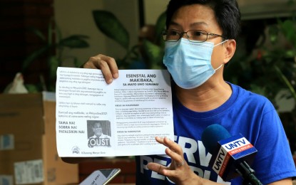 <p><strong>HIDDEN AGENDA.</strong> Jerome Adonis, secretary general of the labor group Kilusang Mayo Uno and organizer of the Tulong Obrero community pantry in Project 3, Quezon City, shows a sample of the anti-government flyers they distribute together with free goods on Thursday (April 22, 2021). Pantries should be allowed to operate unless health protocols are not being observed, according to Presidential Spokesperson Harry Roque during a media briefing on Tuesday.  <em>(PNA photo by Robert Afiller)</em></p>
