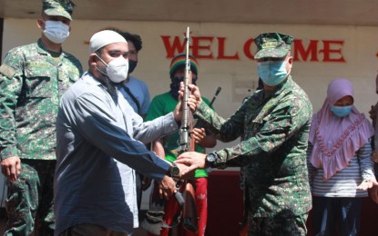 <p><strong>SURRENDER.</strong> An Abu Sayyaf Group member (left) hands over an M-14 rifle to 4th Marine Brigade Commander Col. Hernanie Songano during the surrender ceremony on Friday (April 23, 2021) in Panamao, Sulu. Four bandits and six supporters yielded to the military at the headquarters of the Marine Battalion Landing Team-1 in Barangay Seit Lake. <em>(Photo courtesy of Joint Task Force Sulu)</em></p>