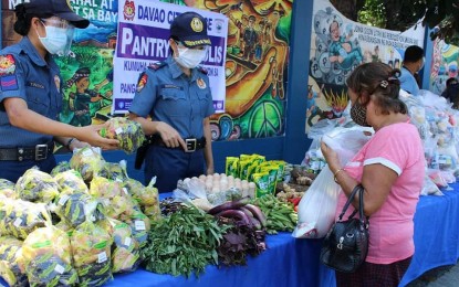 <p><strong>'PANTRY NG PULIS.'</strong> Personnel of the Davao City Police Office attend to a woman who avails of the goods at the “Pantry ng Pulis’ along San Pedro Street in Davao City. Aside from the city's police headquarters, 15 police stations have also mounted their own community pantries. <em>(Photo courtesy of DCPO)</em></p>