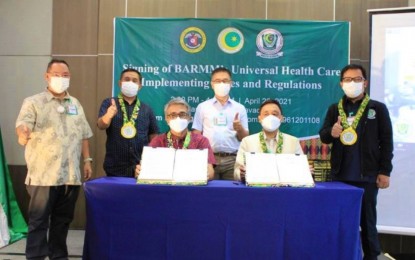 <p><strong>BARMM HEALTH PROGRAM</strong>. Dr. Abdullah Dumama (seated, left), DOH Undersecretary for Visayas and Mindanao field implementation, and Dr. Bashary Latiph, BARMM health minister (seated, right) show the signed IRR of Bangsamoro Universal Health Care (UHC) along with other BARMM health officials following signing ceremonies in Davao City on Monday (April 26, 2021). The UHC law, which President Rodrigo Duterte signed in February 2019, automatically includes all Filipinos into the national health insurance program under the Philippine Health Insurance Corporation.<em> (Photo courtesy of MOH-BARMM)</em></p>