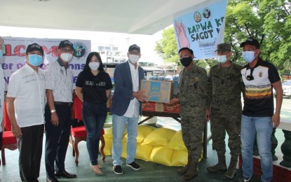<p><strong>FOOD AID. </strong>JTF-NCR chief, Brig. Gen. Marcellano Teofilo (3rd from right) receives a box of food items from PMA Class 1983 president and Interior Undersecretary Bernardo Florece (4th from left) during the turnover of donations in Camp Aguinaldo, Quezon City on Tuesday (April 27, 2021). The donation which contains 150 sacks of rice, 6,000 cans of sardines and 6,000 packs of instant noodles will be distributed to various community pantries in Metro Manila. <em>(Photo courtesy of JTF-NCR)</em></p>
