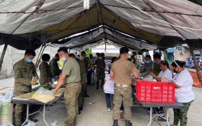 <p><strong>'BAYANIHAN' ALIVE.</strong> Troops, civilian volunteers and officials of Barangay Socorro, Quezon City work together in preparing meals for residents on Thursday (April 29, 2021). The AF has distributed 3,000 food packs to residents of the village through its mobile kitchen. <em>(Photo courtesy of AFP Public Affairs Office)</em></p>