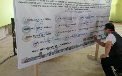 <p><strong>COVENANT.</strong> Housing Secretary Eduardo del Rosario signs a commitment pact with Batangas local government units on Friday (April 30, 2021) to hasten the delivery of assistance to victims of the January 2020 Taal Volcano eruption. A PHP30-million grant will be distributed to 15 cities and municipalities severely affected by the eruption. <em>(Photo courtesy of DHSUD)</em></p>