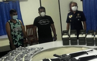 <p><strong>ILLEGAL GUNS</strong>. Some of the high-powered firearms and other illegal items seized from suspects Staff Sgt. Abdul Gani Macadla (left) and former Police Officer 1 Warden Husain Legawan (center), who were stopped at a checkpoint of the Regional Highway Patrol Unit 12 (Soccsksargen) in Barangay Apopong, General Santos City on Friday (May 7, 2021). Also in photo is city police director, Col. Gilberto Tuzon. <em>(PNA-GenSan photo by Richelyn Gubalani)</em></p>