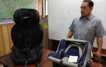 <p><strong>CHILD RESTRAINT SYSTEM</strong>. Land Transportation Office-Cordillera director Francis Ray Almora shows samples of the child restraint seats which vehicle owners must have to protect children-passengers. He said a child must be seated on it thus he is counted as one passenger for purposes of determining overloading.<em> (PNA photo by Liza T. Agoot)</em></p>