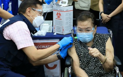<p><strong>PFIZER VAX ROLLOUT.</strong> Health Secretary Francisco Duque III administers the Pfizer Covid-19 vaccine to an 87-year-old dialysis patient Juana Ramos during the ceremonial rollout of the US-made jabs at the Makati Medical Center on Thursday (May 13, 2021). He said the goal of the government is to bring down the Covid-19 cases to less than 2,000 a day nationwide. <em>(PNA photos by Robert Oswald P. Alfiler)</em></p>