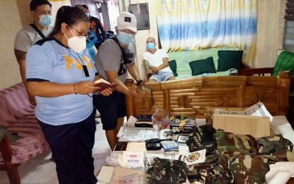 <p><strong>BUY-BUST</strong>. Lt. Col. Jacquiline Puapo, Malolos City police chief (left), examines the confiscated pieces of evidence from Dionisio Evangelista (seated), an active member of the CPP-NPA who was arrested in a drug buy-bust operation on Tuesday (May 18, 2021) in Barangay Anilao, City of Malolos, Bulacan. Seized from the possession of the suspect were five pieces of heat-sealed transparent plastic sachets containing shabu, seven bullets, buy-bust money, and other subversive items. <em>(Photo courtesy of Malolos PNP)</em></p>