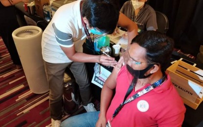 <p><strong>GET THAT VAX.</strong> Randy Roncillo receives his first dose of the Sinovac Covid-19 vaccine at the opening of Taguig City's ninth vaccination hub at the Cinema 1 of the Venice Grand Canal Mall on Wednesday (May 19, 2021). Mayor Lino Cayetano said the city will open its mega vaccination hubs to residents of other cities in the National Capital Region and other parts of the country after completing the vaccination of its eligible population by November. <em>(PNA photo by Lloyd Caliwan)</em></p>