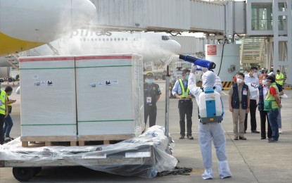 <p><strong>500K MORE VACCINES</strong>. An airport personnel in PPE gears disinfects cargo boxes containing 500,000 more doses of the government-procured Sinovac's CoronaVac vaccine that arrived on board a Cebu Pacific flight at the Ninoy Aquino International Airport Terminal 2 in Pasay City on Thursday (May 20, 2021). The new shipment brought the country’s total number of the China-made vaccine so far to 5.5 million, including 1 million donated by the Chinese government.<em> (PNA photo by Avito C. Dalan)</em></p>