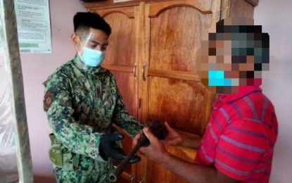 <p><strong>BACK TO FAMILY</strong>.  “Ka Arvin” (right), hands over to Police Corporal Rodriguez Ajochay (left), the homemade firearm he brought with him on May 19, 2021 when he surrendered to the Natonin, Mountain Province municipal police. The surrenderer said he decided to go back to his family and to the fold of the law after realizing he has spent years of uncertainty with the New People’s Army. (<em>Photo courtesy of Natonin PNP</em>) </p>