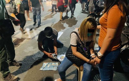 <p><strong>FIXER FALLS.</strong> A police officer conducts an inventory of evidence during an entrapment operation which led to the arrest of Evalyn Aleman (2nd from right) in Taguig City on Thursday (May 27, 2021). Aleman was arrested for alleged fixing activities in the recruitment for police applicants. <em>(Photo courtesy of PNP)</em></p>