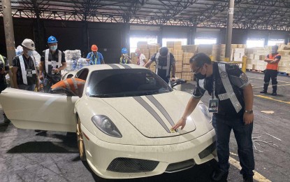 <p><strong>BUSTED.</strong> Customs officers inspect one of three luxury cars concealed in a shipment of used clothing at Manila International Container Port (MICP) on Wednesday (June 2, 2021). This came a week after Customs officers intercepted four luxury cars worth PHP10 million which were also hidden in a shipment of used clothing. <em>(Photo courtesy of BOC)</em></p>