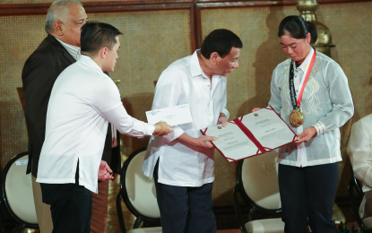 <p><strong>US OPEN CHAMPION</strong>. President Rodrigo Roa Duterte takes time to appreciate the gold medal won by golfer Yuka Saso (right) in the Asian Games while awarding the Presidential citation to the latter during a ceremony at the Rizal Hall in Malacañan Palace on Sep. 12, 2018. Malacañang on Monday (June 7, 2021) hailed Saso for becoming the first Filipino to win the US Open golf championship on Saturday (Philippine time). <em>(Presidential photo by Rey Baniquet)</em></p>