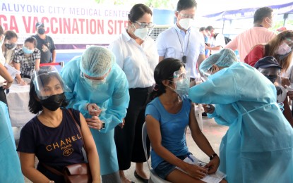 <p><strong>SAFETY NET.</strong> Two market vendors receive their initial Sinovac shots during the vaccination for the A4 priority group at the Mega Tent 1 of Mandaluyong City Hall on Monday (June 7, 2021). The A4 group includes economic front-liners and uniformed personnel. <em>(PNA photo by Joey O. Razon)</em></p>