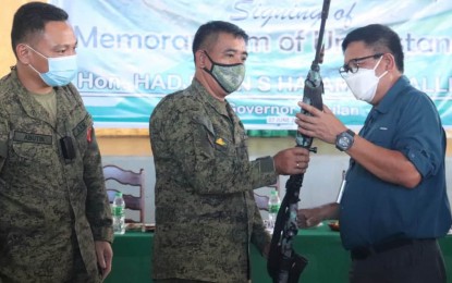 <p><strong>TURNOVER.</strong> Basilan Gov. Hadjiman Hataman-Salliman (right) and Brig. Gen. Domingo Gobway, Joint Task Force-Basilan commander (center), inspect one of the recovered firearms on Monday (June 7, 2021) during the signing of the memorandum of agreement on the implementation of the Small Arms and Light Weapons program that seeks to minimize, if not eradicate, unlicensed guns. Also in photo is Lt. Col. Egverr Jonathan Abutin, commander of the 18th Infantry Battalion. <em>(Photo courtesy of JTF-Basilan)</em></p>