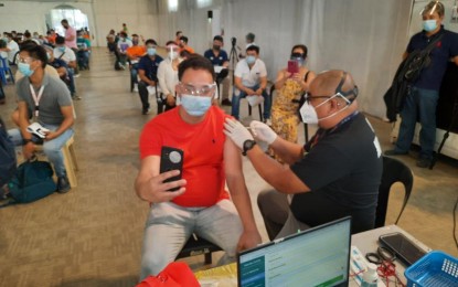 <p><strong>1ST LAYER OF PROTECTION.</strong> A seafarer takes a selfie while receiving his first shot of the Covid-19 vaccine at the Palacio de Maynila on Thursday (June 17, 2021). Mayor Isko Moreno invited all seafarers and other overseas workers who are scheduled to be deployed within the next four months to get vaccinated in the city. <em>(PNA photo by Marita Moaje)</em></p>