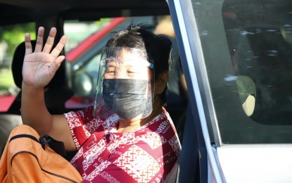 <p><strong>GOING HOME.</strong> Imelda Villena, 55, happily waves goodbye as she leaves the National Housing Authority compound in Quezon City with her son, Erico, on Friday (June 18, 2021). They are now in Leyte as beneficiaries of the Balik Probinsya, Bagong Pag-asa Program of the national government.<em> (PNA photo by Robert Alfiler)</em></p>