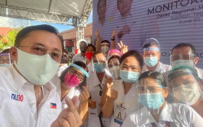 <p><strong>PROTOCOLS.</strong> Senator Bong Go and medical workers of Davao Regional Medical Center in Tagum City, Davao del Norte, all wearing masks and face shields, pose for a souvenir photo on June 10, 2021. Go visited the hospital’s Malasakit Center, the 47th branch of the one-stop center that opened in October 2019, and turned over PHP200 million for the purchase of new medical equipment for cancer patients. <em>(Photo courtesy of SBG)</em></p>