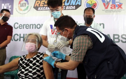 <p><strong>10 MILLIONTH JAB</strong>. Health Secretary Francisco Duque III administers the 10 millionth dose of Covid-19 vaccine to 74-year-old Nieves Catacutan in a ceremonial vaccination at the Valenzuela Astrodome in Valenzuela City on Monday (June 28, 2021). The country has so far administered 10,065,414 doses of Covid-19 vaccine. <em>(PNA photo by Jess M. Escaros Jr.)</em></p>