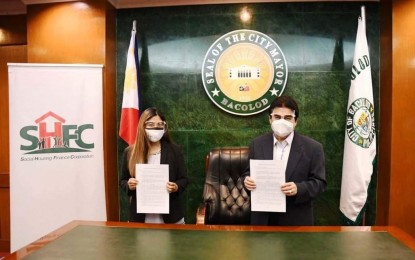 <p><strong>PARTNERSHIP</strong>. Bacolod City Mayor Evelio Leonardia (right) and Social Housing Finance Corp. representative Kara Cuarom show the signed memorandum of understanding for the PHP185.6-million housing project for a group of City Hall employees on a 5.4-hectare property in Barangay Felisa. The two government entities sealed the partnership in rites at the Bacolod City Government Center on June 29, 2021.<em> (Bacolod City PIO)</em></p>