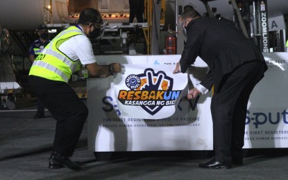 <p><strong>VIRUS ANTIDOTE.</strong> Vaccine czar Secretary Carlito Galvez Jr. (left) and Russian Ambassador to the Philippines Marat Pavlov place a ‘ResBakuna’ sign on a crate with Sputnik V jabs at the Ninoy Aquino International Airport Terminal 3 in Pasay City on Friday night (July 9, 2021). The 132,200 doses of Covid-19 vaccines delivered were all government-procured.<em> (PNA photo by Joey Razon)</em></p>