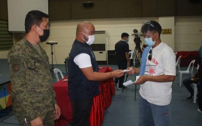 <p><strong>CASH AID FOR EX-REBELS</strong>. Davao de Oro Governor Jayvee Tyron Uy (center) hands over a check to a former rebel (FR) at the provincial capitol on Monday (July 14, 2021). A total of P1.7-million cash assistance was given to some 45 FRs as part of the government’s efforts to help them start a new life and become productive members of society. <em>(Photo courtesy of 1001st Infantry Brigade)</em></p>