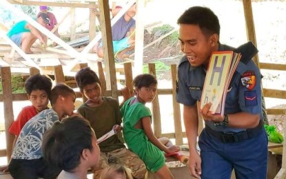 <p><strong>TEACHER COP.</strong> Pat. Noel Amor teaches reading to IP kids in Barangay Dagohoy, Talaingod, Davao del Norte in this undated photo. Amor continues to help deliver modules and teach children in the far-flung village despite getting his right hand paralyzed after being shot by NPA rebels in an attack. <em>(Photo courtesy of PNP)</em></p>
