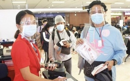 <p><strong>VACCINATED FLYERS</strong>. An AirAsia Philippines ground staff at the Mactan-Cebu International Airport attends to passengers boarding a domestic flight. AirAsia said Thursday (July 15, 2021) fully vaccinated personnel assisted two flights carrying vaccinated flyers.<em> (Photo courtesy of AirAsia)</em></p>