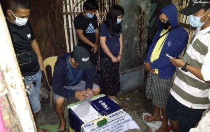 <p><strong>DRUG HAUL</strong>. An operative of the Bacolod City Police Office City Drug Enforcement Unit conducts an inventory of the suspected shabu seized from two suspects (standing, center) during a buy-bust in Barangay 19 on Saturday night (July 17, 2021). Both suspects yielded five sachets of shabu weighing about 16 grams valued at P108,800. <em>(Photo courtesy of Bacolod City Police Office)</em></p>