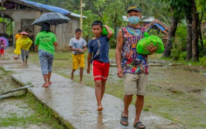 <p><strong>BDP BENEFICIARIES</strong>. Residents of Nagoocan village in Catubig, Northern Samar carry relief goods received during a service caravan this February 17, 2021. The village is one of the recipients of the Barangay Development Program this year. <em>(Photo courtesy of DILG Region 8)</em></p>