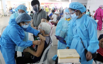 <p><strong>SINOVAC VAX.</strong> Adelina Dumduman (seated), 71, receives her first Sinovac jab from health worker Diana Elnes at a mall in Dasmariñas City, Cavite on June 29, 2021. Dumduman is now among the 2,760,074 senior citizens already inoculated against Covid-19 as of July 18. <em>(PNA photo by Gil Calinga)</em></p>