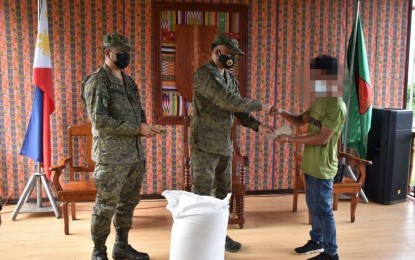 <p><strong>INITIAL AID</strong>. Maj. Gen. William Gonzales, 11th Infantry Division commander (center), and Brig. Gen. Antonio Bautista Jr., 1101st Infantry Brigade commander, hand over cash and a 50-kilo sack of rice to one of the 16 Abu Sayyaf surrenderers as initial aid. The bandits surrendered on Thursday (July 22, 2021) at the headquarters of 1101st IB in Sitio Bayog, Barangay Samak, Talipao, Sulu. <em>(Photo courtesy of the 11ID Public Affairs Office)</em></p>
