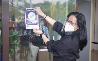 <p><strong>SAFETY SEAL</strong>. SBMA chairman and administrator Wilma T. Eisma posts a safety seal sign at the entrance of the Harbor Point Ayala Mall at the Subic Bay Freeport on Monday (July 26, 2021). The safety seal is valid for six months and is renewable. <em>(Photo courtesy of SBMA)</em></p>