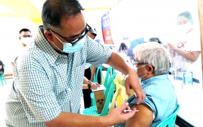 <p><strong>ON DUTY.</strong> Rev. Fr. Ross dela Cruz, a registered nurse, administers the Covid-19 vaccine to Fr. Ponpon Marcelo, 78, at the Parokya ng Pagkabuhay parish in Novaliches, Quezon City on June 28, 2021. On July 27, the Philippines recorded its highest daily vaccination output at 659,029 doses. <em>(PNA photo by Ben Briones)</em></p>