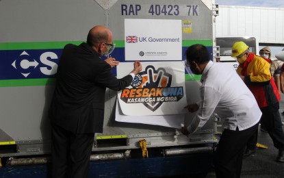 <p><strong>UK DONATION.</strong> National Task Force Against Covid-19 chief Secretary Carlito Galvez Jr. (right) and British Ambassador Daniel Pruce place the 'Resbakuna' seal on the shipment of 415,040 doses of United Kingdom-donated AstraZeneca at the Ninoy Aquino International Airport Terminal 3 in Pasay City on Monday (Aug. 2, 2021). The first tranche of the AstraZeneca delivery is part of the UK's commitment to provide 100 million vaccines for developing countries, including the Philippines. <em>(PNA photo by Avito C. Dalan)</em></p>