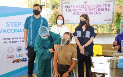<p><strong>INOCULATING TOURISM WORKERS</strong>. Palawan 1st District Rep. Franz Alvarez (L-R from behind), El Nido Mayor Edna Gacot-Lim, and Tourism Secretary Bernadette Romulo-Puyat witness the ceremonial vaccination at the Lio Tent at Huni, Lio. The DOT on Tuesday (August 3, 2021) says it targets to inoculate at least 31,000 tourism workers in Palawan. <em>(DOT photo)</em></p>