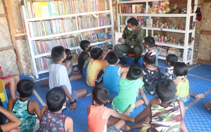 <p><strong>LIBRARY FOR KIDS</strong>. A soldier tells a story to children inside a mini-library in Allen, Northern Samar in this undated photo. Army engineers built a mini-library for children in Allen, Northern Samar to help them practice their reading skills during this pandemic. <em>(Photo courtesy of Philippine Army 543rd Engineer Construction Battalion)</em></p>