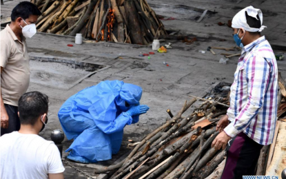 <p><strong>GLOBAL CASES</strong>. A family member wearing a protective suit prays in front of the pyre to his relative before cremation at a crematorium in New Delhi, India on May 21, 2021. Global Covid-19 cases surpassed 200 million on Wednesday, according to data from Johns Hopkins University. (Xinhua/Partha Sarkar)</p>