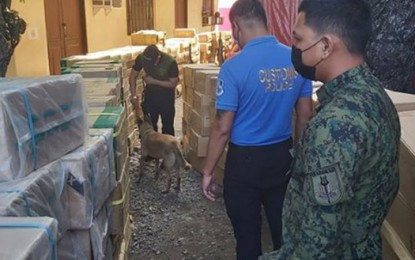 <p><strong>ILLEGAL SHIPMENT.</strong> Joint team of the 2nd Zamboanga City Mobile Force Company (2ZCMFC) and Bureau of Customs (BOC) seize a shipment of some P11.2 million worth of smuggled cigarettes off Zamboanga City on Thursday (August 5, 2021). Photo shows a K9 unit of the Philippine Drug Enforcement Agency (PDEA) inspecting its contents for illegal drugs. (<em>Photo courtesy of the 2ZCMFC)</em></p>
